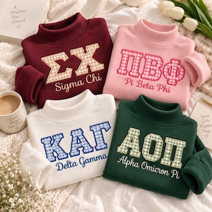 Könnte beinhalten: Vier Sweatshirts mit Stehkragen in Kastanienbraun, Rosa, Weiß und Dunkelgrün. Jedes zeigt große, gestickte griechische Buchstaben mit Vichy-Muster und den entsprechenden Namen der Studentenverbindung in Schreibschrift darunter.
