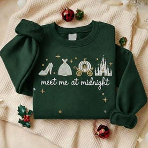Puede incluir: Sudadera verde oscuro con la frase "meet me at midnight" e im&aacute;genes bordadas de un zapato de tac&oacute;n, un vestido, un carruaje y un castillo. La sudadera tiene mangas largas y cuello redondo.