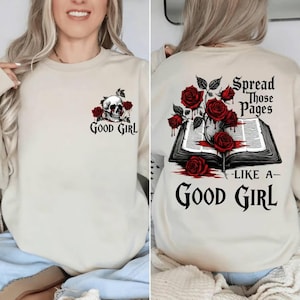 May include: Beige sweatshirt with a skull and roses graphic on the front, and a book and roses design on the back. The text on the front says "Good Girl", and the back says "Spread Those Pages Like A Good Girl".