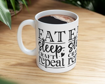 May include: White ceramic mug with black text that reads "Eat, Sleep, Craft, Repeat" with a heart symbol between "Sleep" and "Craft".
