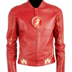 May include: A red jacket featuring a central circular emblem with a gold lightning bolt design. The jacket includes gold-coloured piping along the sleeves and gold lightning bolt accents near the hemline, with a full-length front zip closure.
