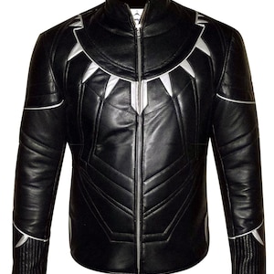 Puede incluir: Chaqueta de cuero negra con detalles plateados. La chaqueta presenta un cuello alto, una cremallera completa y diseños geométricos plateados en el pecho y los hombros. Las mangas tienen ribetes plateados en los puños. Una prenda de abrigo elegante.
