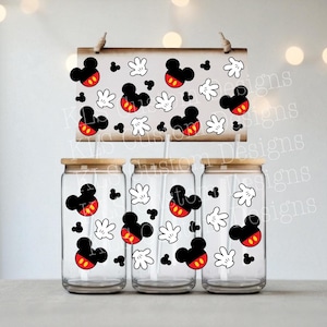 May include: Three clear glass tumblers with bamboo lids and straws, decorated with Mickey Mouse designs. A wooden sign above displays the same pattern. The design includes Mickey's head, gloves, and black dots.