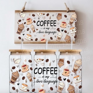 May include: Three glass jars with lids and straws, decorated with a coffee theme. The jars have a brown and white design with coffee cups, coffee beans, and hearts. The text on the jars reads "Coffee - is my love language".