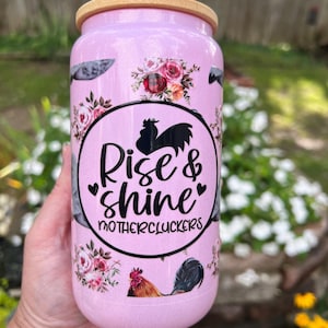 May include: Pink insulated tumbler with a bamboo lid. The tumbler has a floral design with roosters and the text "Rise & shine Mothercluckers".