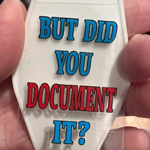 May include: White motel key tag with the text "But did you document it?" in blue and red lettering.