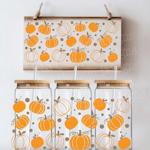 Può includere: Tre bicchieri di vetro con coperchi e cannucce in bambù, decorati con disegni di zucche arancioni. Un cartello di legno sopra presenta anche grafiche di zucche. Perfetto per eventi a tema autunnale.