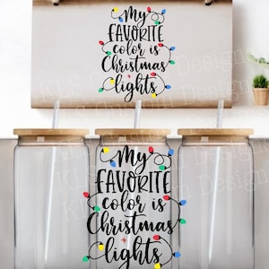 May include: Three clear glass tumblers with wooden lids and straws. Each tumbler has a design of colorful Christmas lights with the text "My favorite color is Christmas lights".