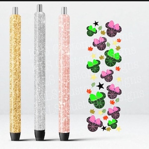Puede incluir: Tres bolígrafos con purpurina dorados, plateados y rosas, cada uno con punta negra y parte superior plateada. A la derecha, un diseño decorativo de cabezas de ratón de dibujos animados con telarañas, lazos, estrellas y hojas.