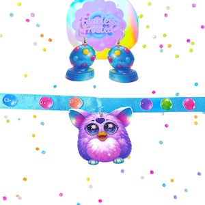 May include: A collection of colorful accessories, including a pendant and earrings. The pendant is a purple, fluffy creature with large eyes, hanging from a blue ribbon. The earrings are blue with colorful polka dots. The background features confetti.