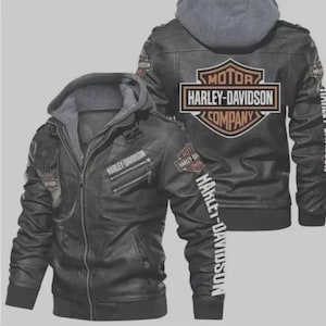 Könnte beinhalten: Schwarze Kunstlederjacke mit grauem Kapuzeneinsatz. Die Jacke hat das Harley-Davidson-Logo auf Brust, Rücken und Ärmel. Die Jacke hat einen Reißverschluss und mehrere Taschen. Das Harley-Davidson-Logo ist orange und weiß.