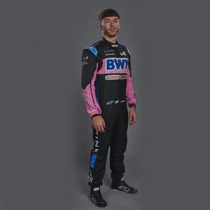 Può includere: Tuta da corsa nera con dettagli rosa e blu. La tuta presenta loghi di sponsor, tra cui "BWT" e "Castrol EDGE". Il nome del pilota, "Gasly", è visibile. Il pilota indossa scarpe da corsa nere.