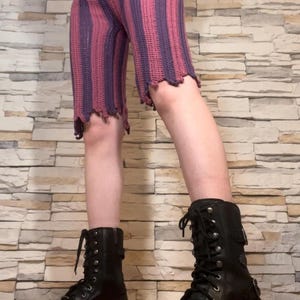 A person wearing purple and magenta striped crochet pants based off of Jinx from Arcane