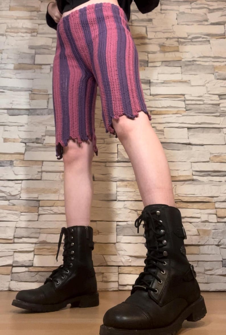 A person wearing purple and magenta striped crochet pants based off of Jinx from Arcane