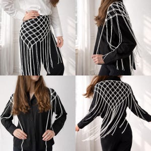 May include: A white macrame overlay featuring a diamond-shaped grid pattern and long, dangling fringe. This versatile piece is shown worn over a white button-down shirt with black trousers and also layered over a black long-sleeve shirt and pants.
