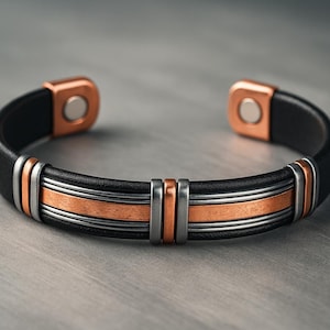 May include: Black leather cuff bracelet with copper and silver-tone metal accents. The bracelet features a magnetic closure and decorative bands of copper and silver. A stylish accessory.