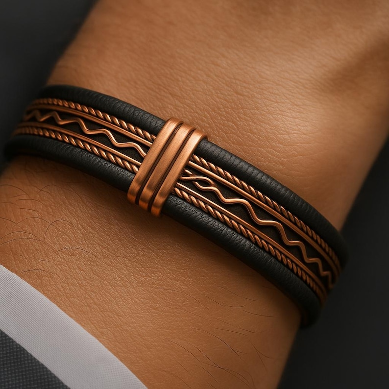 May include: Black leather bracelet with copper-colored metal accents. The bracelet features a central copper bar and decorative copper wire and wave patterns. The bracelet is worn on a wrist, showcasing the design and craftsmanship.