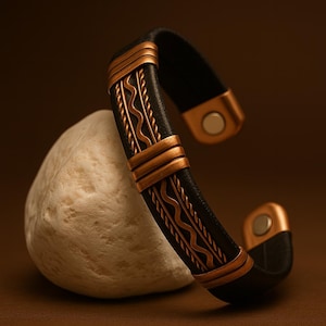 May include: A black leather cuff bracelet with copper-colored metal accents. The bracelet features a decorative wave pattern and is set against a neutral background. The cuff is approximately 2 inches wide.