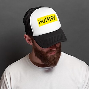 May include: A black and white trucker hat with a yellow patch that says "HUNNY" on it.