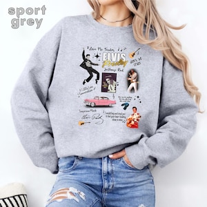 May include: A gray sweatshirt with a graphic print of Elvis Presley. The print includes images of Elvis, a car, and musical notes. The text on the print includes song titles and lyrics. "Love Me Tender", "Jailhouse Rock", "Don't Be Cruel", "A Little Less Conversation", "Suspicious Minds", and "I Would Beg and Steal Just to Feel Your Heart Beating Close to Mine" are included in the print.