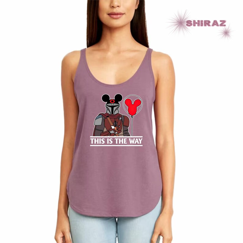 May include: A purple tank top with a graphic of a Mandalorian character wearing Mickey Mouse ears and holding a red balloon. The text "This is the Way" is printed below the graphic.