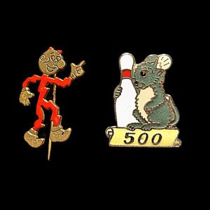 May include: Two vintage bowling pins. One pin features a cartoon figure in red and gold, pointing. The other pin shows a green and cream-colored mouse holding a bowling pin, with the number "500" on a banner.