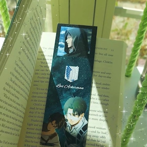 May include: A rectangular bookmark featuring anime character Levi Ackerman from Attack on Titan. The design includes a dark blue starry background, the Survey Corps emblem, and the text Levi Ackerman, with two illustrations of the character.