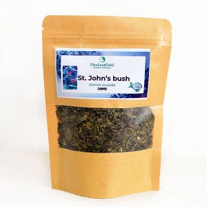 May include: A brown paper bag with a clear window displaying dried green leaves. The bag has a label that reads "St. John's bush (Justicia secunda) Leaves" with a blue and white design. The product is likely a herbal tea or medicinal herb.