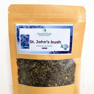 May include: A brown paper bag with a clear window, filled with dried green leaves. A rectangular label displays the text "St. John's bush (Justicia secunda) Leaves" and the brand name "PleazantField". The label has a blue and white background.