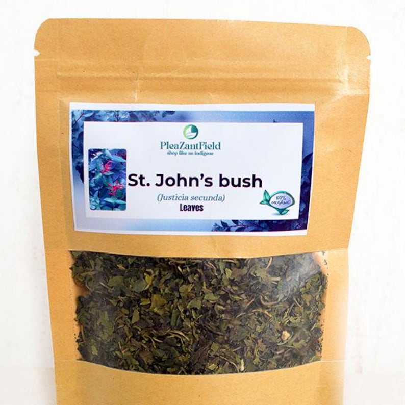 May include: A brown paper bag with a clear window, filled with dried green leaves. A rectangular label displays the text "St. John's bush (Justicia secunda) Leaves" and the brand name "PleazantField". The label has a blue and white background.