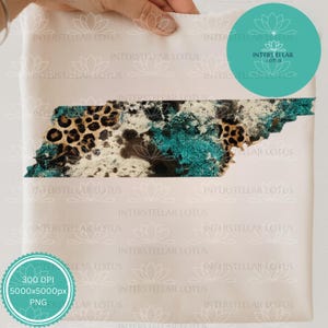 Puede incluir: Un bolso tote de color beige claro con un diseño del contorno del estado de Tennessee. El diseño incorpora estampado de leopardo, purpurina turquesa y colores crema. El bolso tiene el texto "INTERSTELLAR LOTUS" y "INTERS ELLAR LOTUS" impreso.
