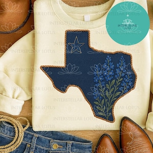 May include: Cream-colored sweatshirt featuring a navy blue Texas-shaped design with a gold star and bluebonnet flowers. The design is outlined with a brown rope-like trim. The sweatshirt is part of a casual clothing collection.