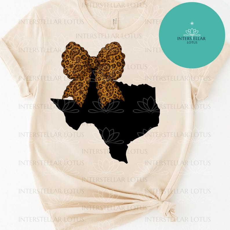 May include: A cream-colored t-shirt featuring a black silhouette of the state of Texas. A large bow with a leopard print design is centered above the state. The shirt has the text "INTERSTELLAR LOTUS" printed around the design.