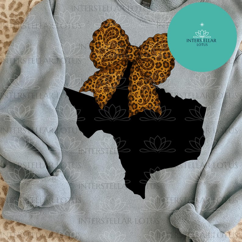 May include: A light blue sweatshirt featuring a black Texas outline with a large bow. The bow has a leopard print design with paisley accents. A teal circle with the text "INTERSTELLAR LOTUS" is in the upper right corner.