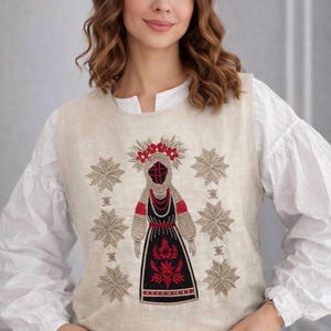 May include: A sleeveless beige linen vest featuring intricate embroidery of a central figure in traditional attire surrounded by six large star-shaped patterns. The embroidery uses black, red, and beige thread to create detailed motifs.