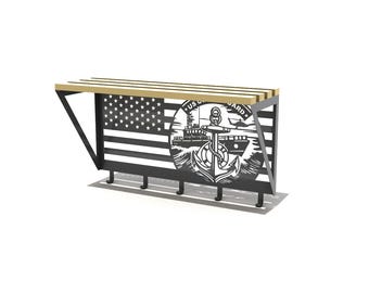 May include: A black metal wall-mounted shelf with a wooden top and four hooks. The shelf features a cut-out design of the American flag and a US Coast Guard emblem with an anchor.