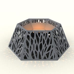 Puede incluir: Un brasero geométrico gris con un diseño calado único. Los lados presentan un patrón de formas orgánicas y el interior es visible. El brasero tiene forma hexagonal y es adecuado para uso en exteriores.