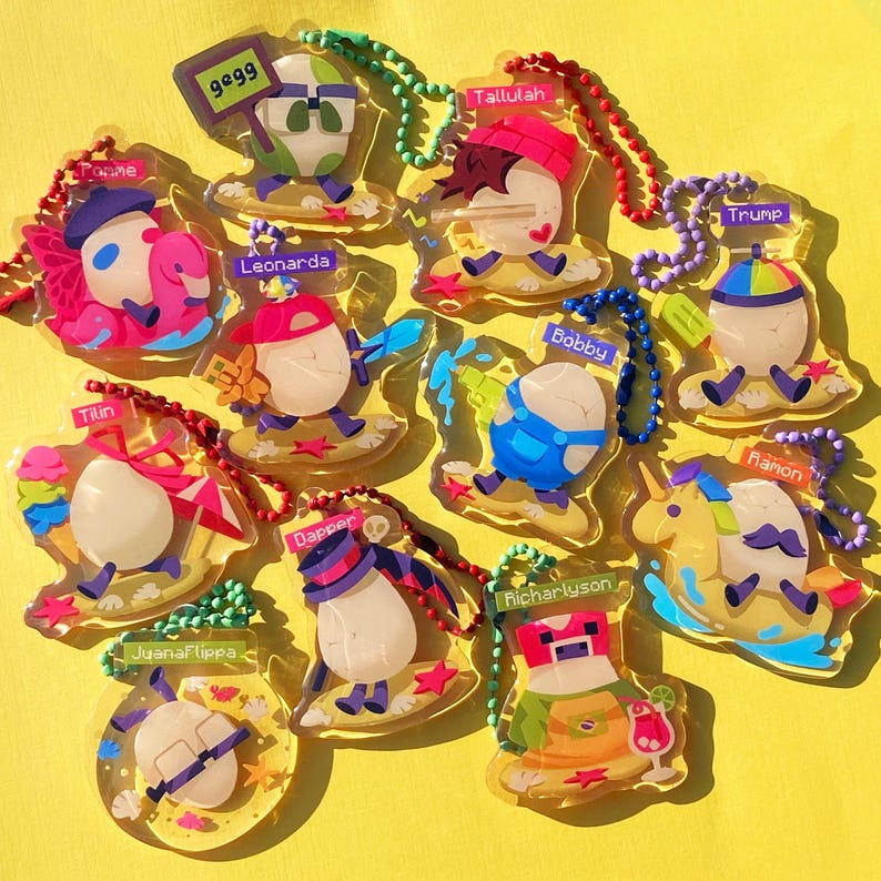 May include: A collection of 12 colorful keychains featuring cartoon characters on a yellow background. Each keychain has a different character with a name, such as 'Bobby', 'Trump', 'Tilli', 'Leonarda', 'Dapper', 'Ramon', 'Richarlison', 'Tallulah', 'Juana Flippa', '9899', 'Toque Me', and 'The character is riding a unicorn.