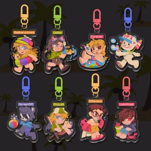 May include: Eight colorful keychains with cartoon characters on them. The keychains are shaped like a circle and have a silver metal ring at the top. Each keychain has a different character and a different color. The characters are: Baghera Jones, Cellbit, Forever, SpreenDMC, PhiLzA, ElMariana, LuzuVlogs, and a white bear. The keychains are all on a black background with palm trees.
