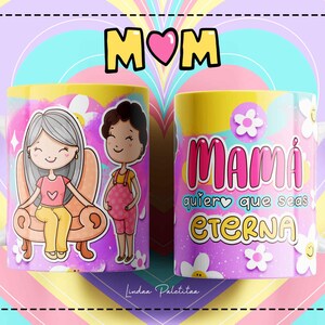 Puede incluir: Una taza de cer&aacute;mica blanca con un dise&ntilde;o rosa, amarillo y azul. La taza presenta una ilustraci&oacute;n de dibujos animados de una mujer sentada en un sof&aacute; y una mujer embarazada de pie junto a ella. El texto "Mami quiero que seas eterna" est&aacute; impreso en la taza.