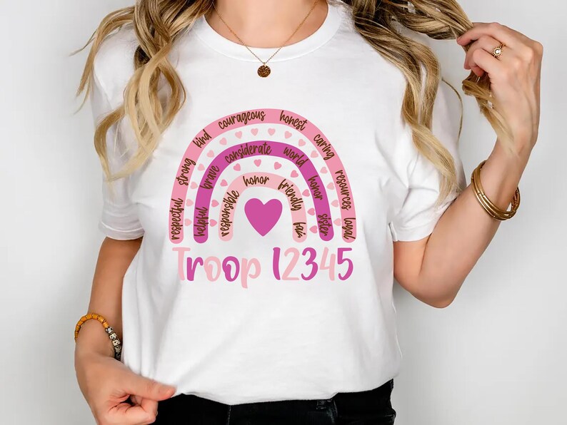 A woman wearing a white t-shirt with a colorful graphic design and text printed on it.
