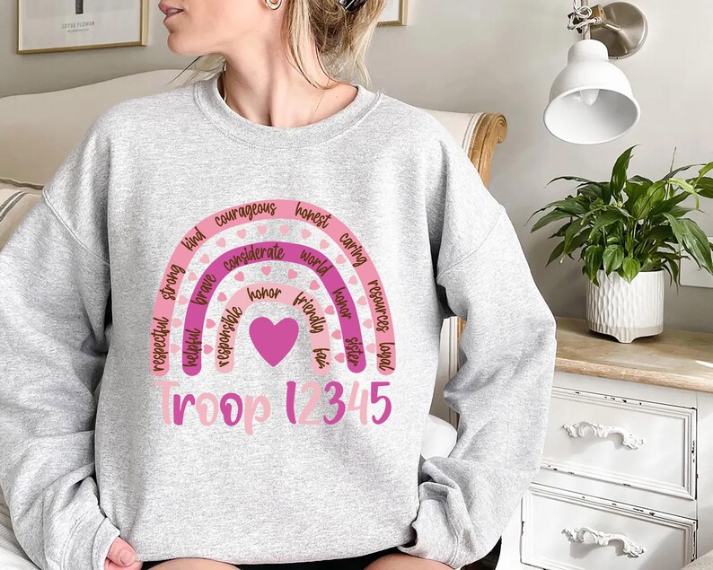 a woman sitting on a bed wearing a sweatshirt with a rainbow