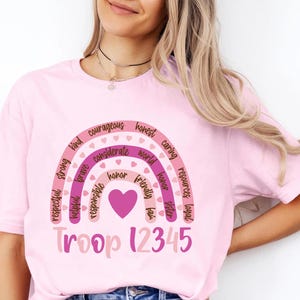 a woman wearing a pink crop top with a rainbow on it