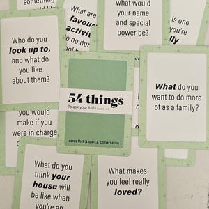 May include: A collection of conversation starter cards with a light green border and various questions printed on them. The cards are titled "54 things to ask your kids" and are designed to spark conversation.