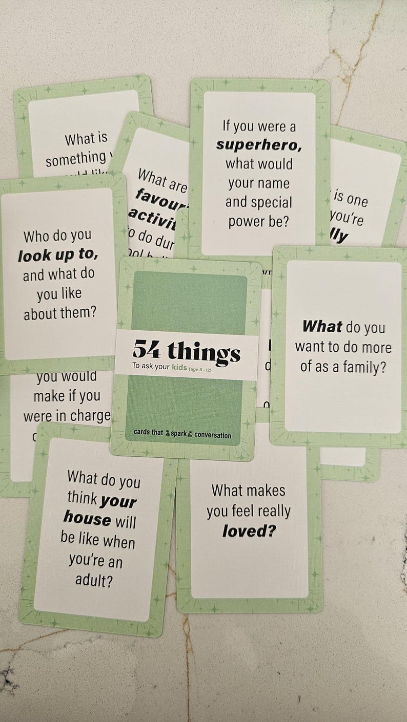 May include: A collection of conversation starter cards with a light green border and various questions printed on them. The cards are titled "54 things to ask your kids" and are designed to spark conversation.