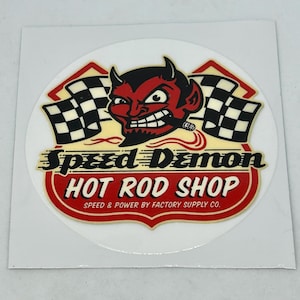 May include: A red and white circular sticker with a cartoon devil holding a cigar and a checkered flag. The text "Speed Demon Hot Rod Shop" is written in a stylized font with the tagline "Speed & Power by Factory Supply Co."