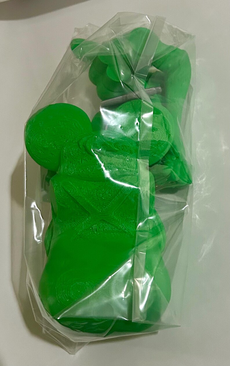 Peut inclure: Des figurines de jouets en plastique vert vif sont emball&eacute;es dans un sac en plastique transparent. Les figurines ont une forme arrondie avec des surfaces textur&eacute;es. Le sac est scell&eacute; avec du ruban adh&eacute;sif transparent. Les jouets semblent neufs.