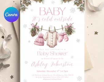 Peut inclure: Une invitation à une baby shower sur le thème de l'hiver. L'invitation présente le texte "BABY It's cold outside" en rose, ainsi que des illustrations de vêtements de bébé et de branches de pin. L'invitation est pour Ashley Johnston.