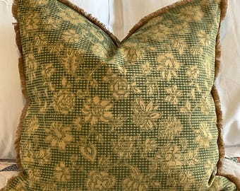 May include: A green and yellow throw pillow with a floral pattern and a brown fringe border.