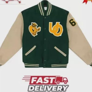 May include: A green and beige varsity jacket with a button-up front. The jacket has a yellow duck patch and a large yellow letter on the front. The sleeves are beige, and the jacket has a ribbed collar and cuffs. The number "6" is on the right sleeve.